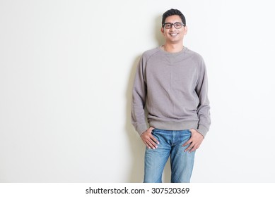 Portrait Of Handsome Casual Indian Male Smiling, Standing On Plain Background With Shadow, Copy Space At Side.