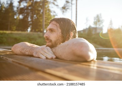 Portrait Of Handsome Caucasiahn Man Swimming In Lake By Pier With Lens Flare