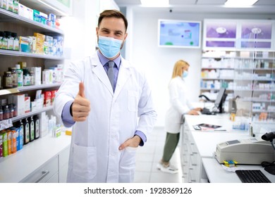 Portrait Of Handsome Caucasian Male Pharmacist With Face Mask Standing In Pharmacy Store.