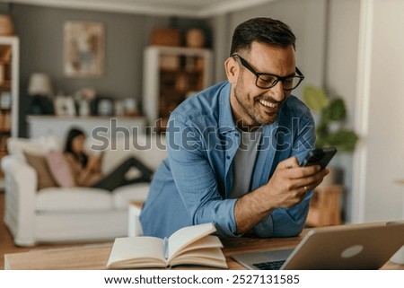 Portrait of a handsome Caucasian man looking at smartphone, working online from his home