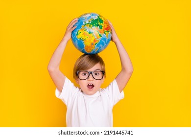 Portrait of handsome cheerful genius funny pre-teen boy schoolkid holding globe on head isolated over bright yellow color background - Powered by Shutterstock