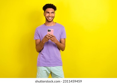 Portrait of handsome cheerful guy hold smart phone beaming smile look empty space isolated on yellow color background - Shutterstock ID 2311459459