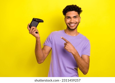 Portrait of handsome cheerful man indicate finger arm hold demonstrate controller isolated on yellow color background - Shutterstock ID 2311459257