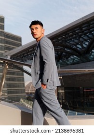 Portrait of handsome Chinese young man in light blue suit and white undershirt walking and looking away with modern city buildings background in sunny day, side view of confident businessman. - Shutterstock ID 2138696381