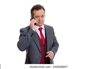 Portrait Of Handsome Confident Caucasian Mature Businessman 55-60 Years Old In Grey Tuxedo And Red Vest. Rich Senior Man Talk By Phone And Looking To Camera On Isolated White Background