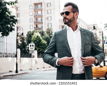 Portrait of handsome confident stylish hipster lambersexual model.Sexy modern man dressed in elegant suit. Fashion male posing in the street background in Europe city at sunset. In sunglasses