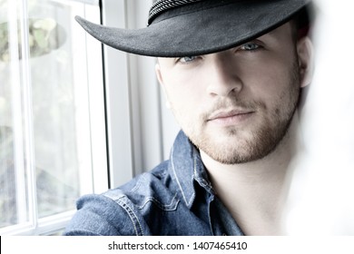 Portrait of handsome cowboy with blue eyes and hat looking at camera
