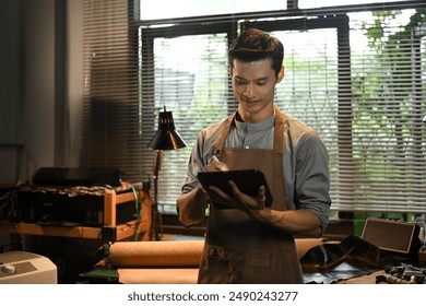 Portrait of handsome craftsman using a digital tablet in leather workshop. Small business and technology concept - Powered by Shutterstock