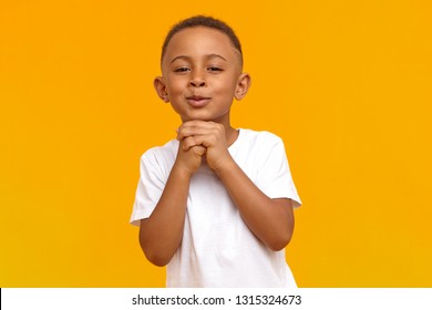 Portrait Of Handsome Cute Ten Year Old African Boy Making Hopeful Adorable Facial Expressions, Holding Hands Clasped Under His Chin, Begging His Mother To Buy Him Expensive Toy. Hope And Innocence