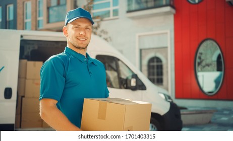 Portrait of Handsome Delivery Man Holds Cardboard Box Package Standing in Modern Stylish Business District with Delivery Van in Background. Smiling Courier On Way to Deliver Postal Parcel to Client