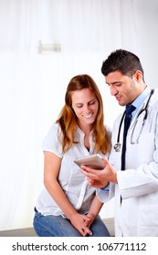 Portrait Of A Handsome Doctor And A Female Patient Looking Something On Tablet PC At Hospital