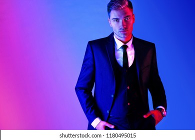 Portrait Of A Handsome Elegant Man Dressed In A Three Piece Suit. In Blue And Red Light. Male Beauty, Fashion.