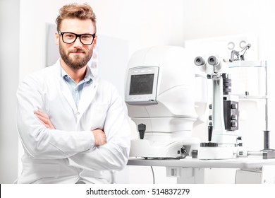 Portrait Of Handsome Eye Doctor Sitting With Ophthalmologic Device In The Cabinet