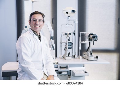 Portrait Of Handsome Eye Doctor Sitting With Ophthalmologic Device In The Cabinet