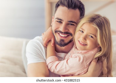 Portrait Of Handsome Father And His Cute Daughter Hugging, Looking At Camera And Smiling