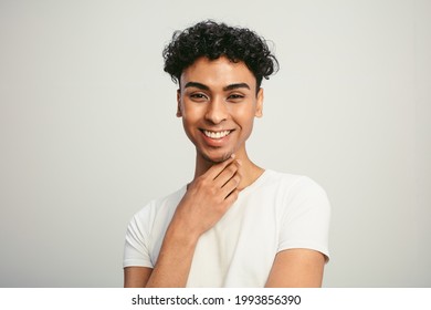 Portrait of a handsome gay man on white background. Smiling young man with cool hairstyle looking at camera.