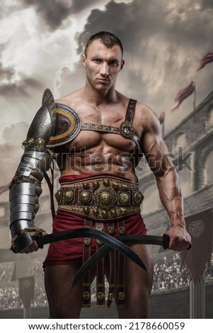 Portrait of handsome gladiator with dual swords dressed in light armor posing in ancient arena.