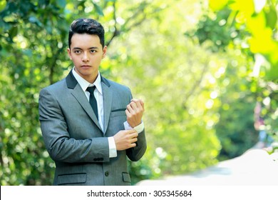 portrait of handsome groom fixing his sleeves with copy space