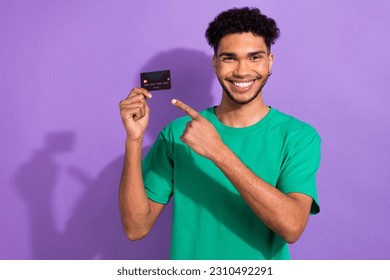 Portrait of handsome guy toothy smile direct finger hand hold debit card isolated on purple color background - Shutterstock ID 2310492291