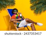 Portrait of handsome guy wear hawaii shirt drink green cocktail sit on chair on summer weekends isolated on yellow color background