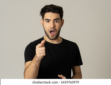 Portrait Of A Handsome Latin Young Man Surprised And Shocked Hearing Great News. Attractive Male Looking Amazed With Wide Eyes And Mouth Open In Surprise. Human Facial Expressions And Emotions.