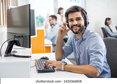 Portrait of handsome male customer service representative, call centre worker, agent, operator, support staff speaking with head set in modern office.