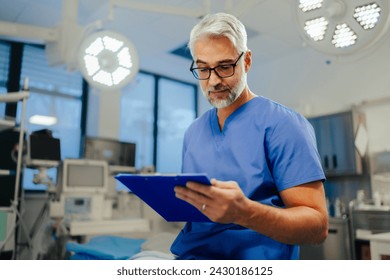 Portrait of handsome male doctor in scrubs. ER doctor examining patient, reading medical test, lab results in clipboard. - Powered by Shutterstock