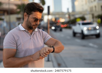 Portrait of handsome male model outdoor. Stylish man dressed in polo. Fashion male posing on the street background. Urban style. Young man walk through the city. Wealthy businessman posing next to