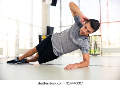 Portrait Of A Handsome Man Doing Side Plank At Gym