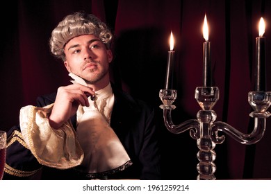 Portrait Of Handsome Man Dressed In Regency Costume And Wig Sitting At Writing Desk.