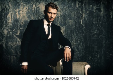 Portrait Of A Handsome Man In An Elegant Suit On A Grunge Background. Studio Shot.