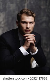 Portrait Of A Handsome Man In An Elegant Suit On A Grunge Background. Studio Shot.