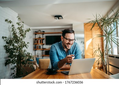 Portrait of a handsome man laughing while looking at laptop.