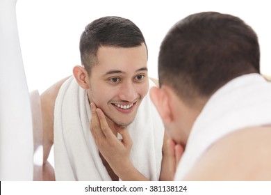 Portrait Of Handsome Man Looking Into The Mirror And Touching His Smooth Face While Smiling