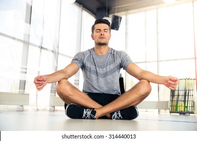 Portrait of a handsome man meditating in fitness gym 