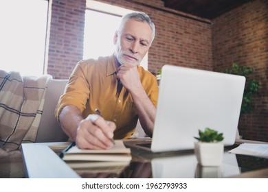 Portrait of handsome man sit on sofa arm on chin look interested notebook write down notes list to do indoors