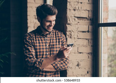 Portrait of a handsome man standing near window in loft room and writing sms - Powered by Shutterstock