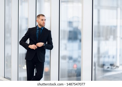 Portrait of handsome man standing in a suit and tie in front of glass door