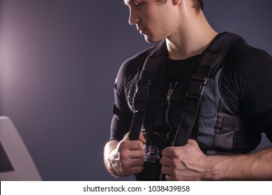 portrait of handsome man wearing ems suit near electro muscle stimulation machine