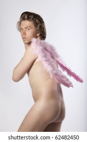 Portrait of a handsome man wearing pink wings. Studio shot. Part of photo series. See more in portfolio