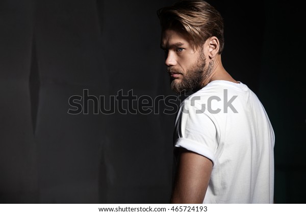 Portrait of a handsome man in a white t-shirt from\
the back
