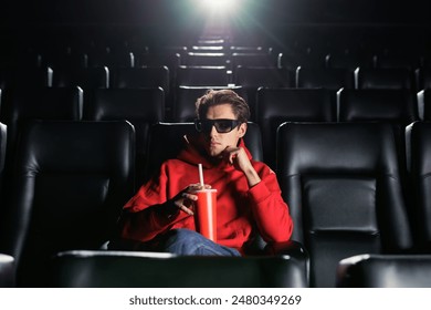 Portrait of a handsome man who drinks soda at the cinema. A lonely man at the premiere of a movie. 3D glasses - Powered by Shutterstock