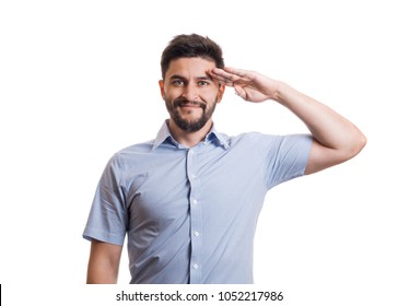 Portrait of handsome man. Young black haired guy with facial hair in blue casual shirt saluting with hand at forehead