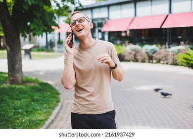 Portrait Of Handsome Mature Businessman Holding Messenger Bag, Wearing Stylish Eyeglasses Looking At Camera. Smiling Middle Aged Man Using Smartphone, Standing On The Street. Mobile Banking Concept