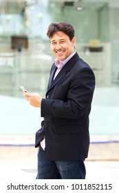 Portrait Of Handsome Mature Businessman With Mobile Phone Standing Outside