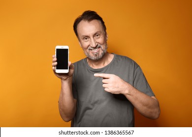 Portrait Of Handsome Mature Man With Mobile Phone On Color Background