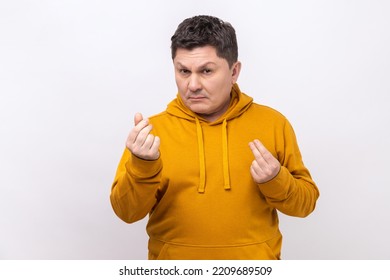 Portrait Of Handsome Middle Aged Man Standing And Looking At Camera With Money Or Italian Gesture With Hand, Wearing Urban Style Hoodie. Indoor Studio Shot Isolated On White Background.