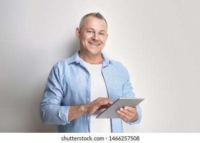 Portrait Of Handsome Middle-aged Man With Tablet PC On Light Background