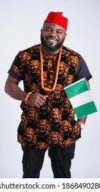 Portrait of handsome Nigerian man dress in Igbo traditional attire and carrying the Nigerian flag