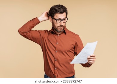 Portrait of handsome pensive middle aged student man wearing eyeglasses holding documents, reading information isolated on beige background. Frustrated businessman, freelancer missed deadline - Powered by Shutterstock